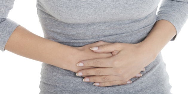 Young casual girl woman is having stomach ache. Over white background.