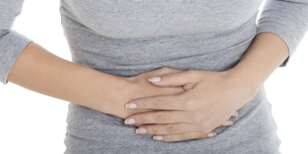 Young casual girl woman is having stomach ache. Over white background.