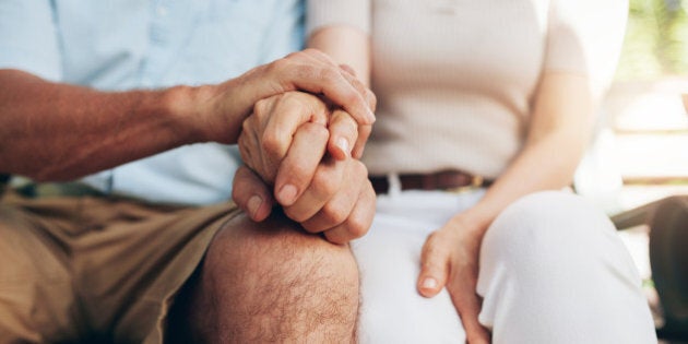 Close up shot of senior couple holding hand. Loving couple sitting together and holding hands. Focus on hands.