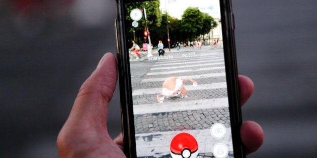 PARIS, FRANCE - AUGUST 17: A man launches a Pokeball to catch a Scarabrute (Pinsir) character while playing Nintendo Co.'s Pokemon Go augmented-reality game, while crossing the road, on the Avenue des Champs Elysees, near Place de la Concorde on August 17, 2016 in Paris, France. (Photo by Edward Berthelot/Getty Images)