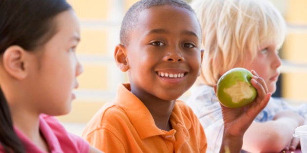 Kindergarten children eating lunch smiling at camera