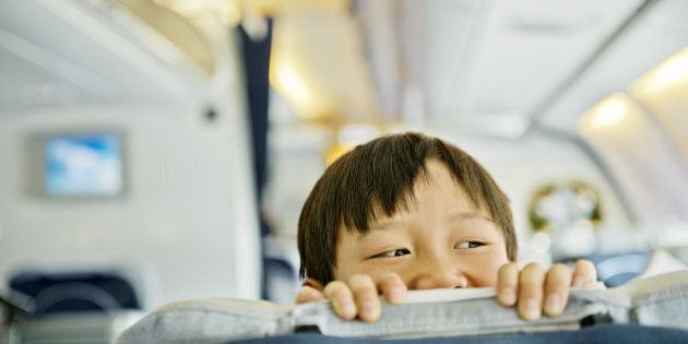 Boy looking over business class seat of plane