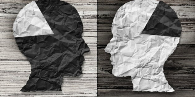 Ethnic equality concept and racial justice symbol as a black and white crumpled paper shaped as a human head on old rustic wood background with contrasting tones as a metaphor for social race issues.