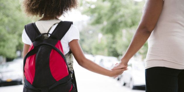 african american mom and daughter hold hands while walking