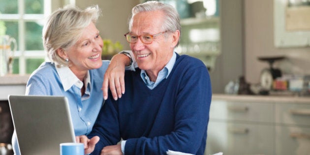 Couple using laptop at kitchen table