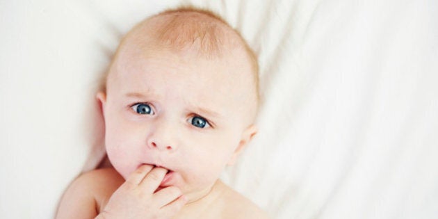 Baby in bed with fingers in mouth