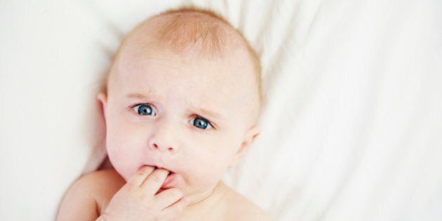 Baby in bed with fingers in mouth