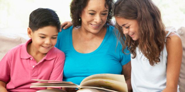 Grandmother Reading With Grandchildren At Home Together