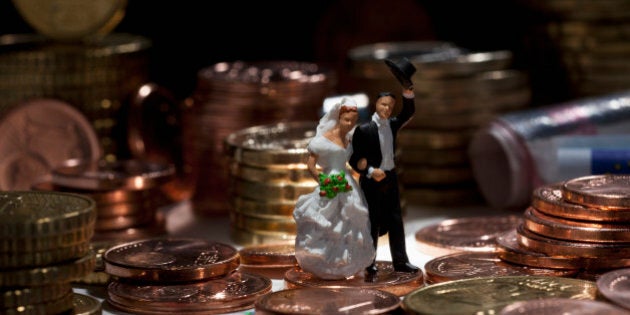 Miniature wedding couple figurines amidst stacks of European Union coins