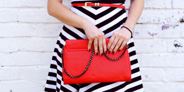 Outdoor Fashionable girl near white street wall .Marine and retro style. striped dress with red handbag clutch