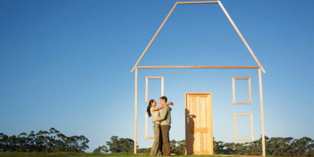 Couple hugging next to vertical house outline