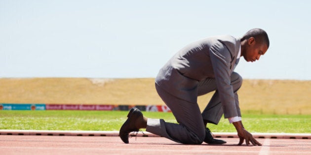 A business man on a track ready to run