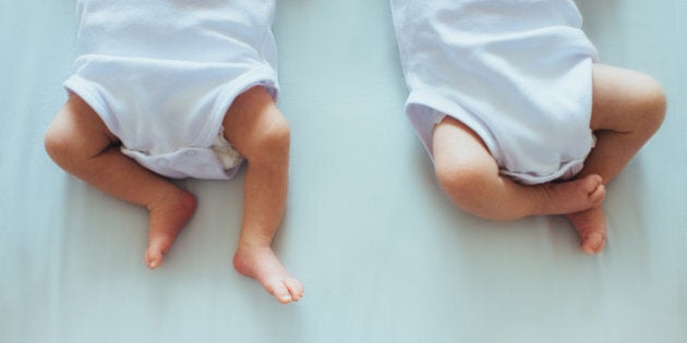 Photo of 2 babies on bed focusing on their legs.