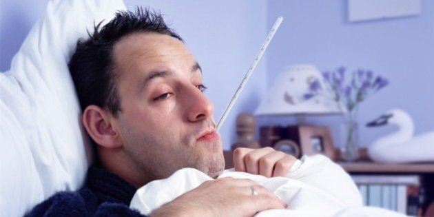 Man lying in bed, with thermometer in mouth, close-up (Enhancement)