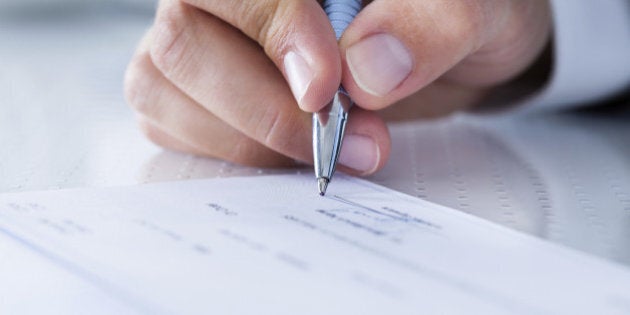 A Male Hand Filling Out The Amount On A Cheque