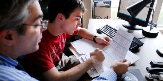 Chris Economou, left, a financial planner, goes over college paperwork with son Thane 18, in their home office in Tulsa, Okla. Saturday Sept. 2, 2006. Financial planners face the same issues that other parents do when their kids head off to college: Should they take checks, debit cards, credit cards _ or some combination of the three? The experts seem to favor checks and debit cards for day-to-day spending with a credit card tucked away somewhere safe for emergencies. (AP Photo/Brandi Simons)