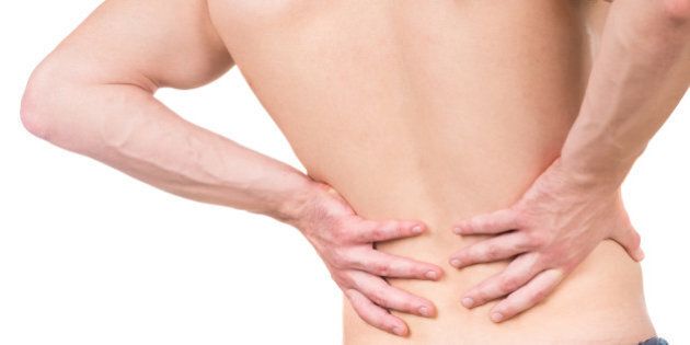 Naked man with lower back pain on white isolated background. Back view. Close-up.