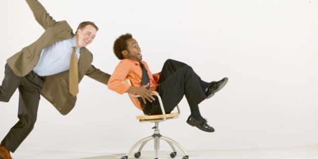Businessmen goofing off with office chair