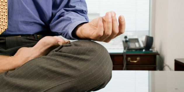 Businessman meditating barefoot on desk
