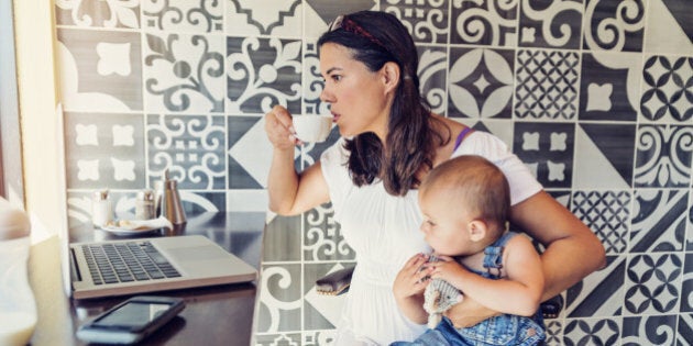 Urban mom balancing work and family in a public cafe. Horizontal.