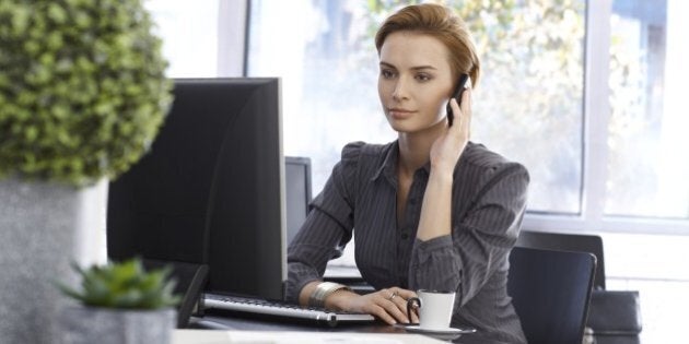 Attractive businesswoman working in green office, talking on mobilephone, using computer..