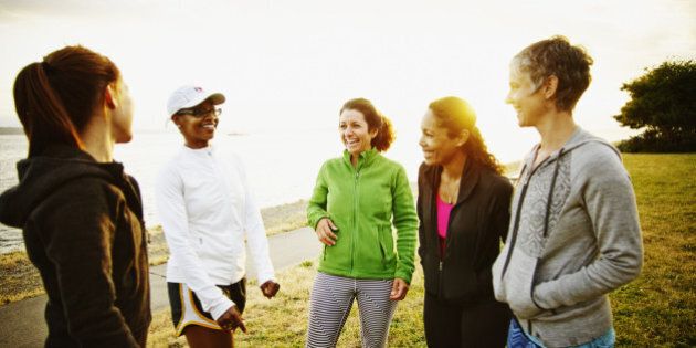 Group of female friends laughing together after completing run at sunset