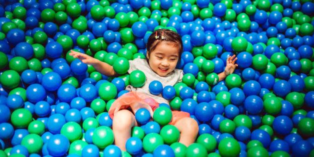 Little girl playing in the ball pit joyfully