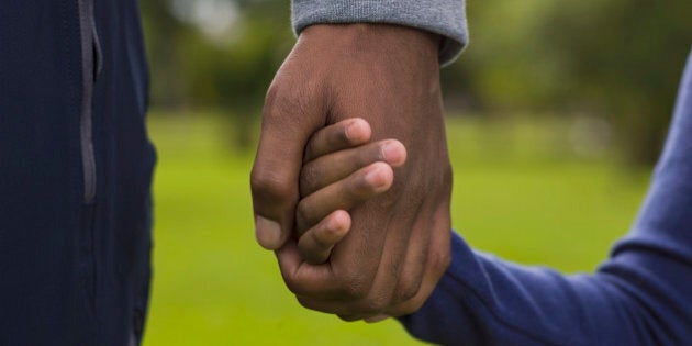 Father and daughter (4-5) holding hands in park, mid section