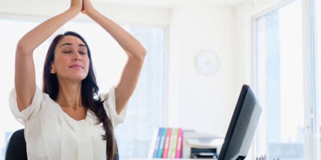 Caucasian businesswoman meditating at desk