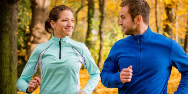 Young couple talking while jogging together in beautiful autumn nature