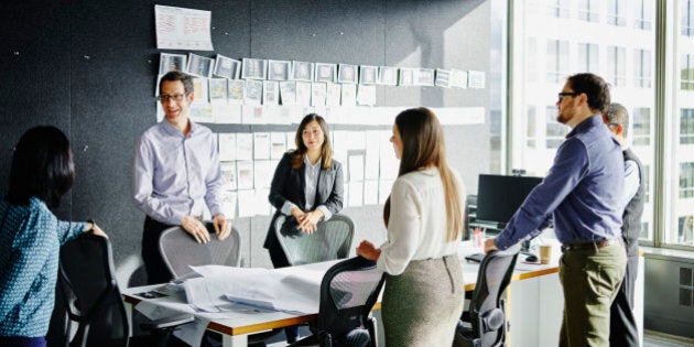 Group of businesspeople beginning project planning meeting at conference table in office