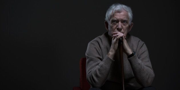Thoughtful elder man sitting in a dark room