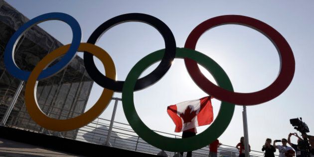 Canada gymnast Rosie MacLennan holds her country's flag while posing for a photograph in front of the Olympic Rings at the Olympic Park ahead of the 2016 Summer Olympics in Rio de Janeiro, Brazil, Friday, Aug. 5, 2016. (AP Photo/Julio Cortez)