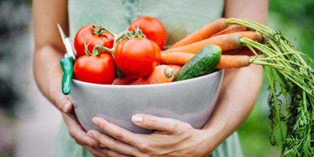 Close-up of a woman holding a bowl with freshly harvested vegetables