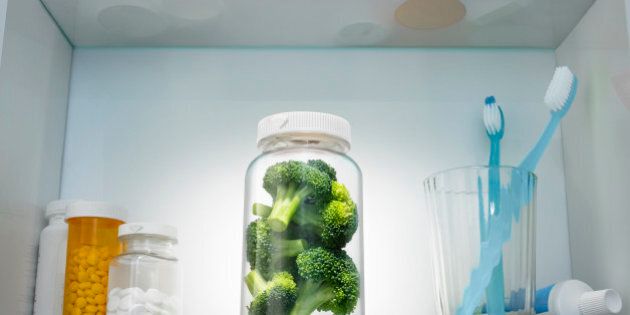 Pieces of broccoli in a pill bottle in a medicine cabinet. The image was is a staged set built and designed by Stephen Swintek