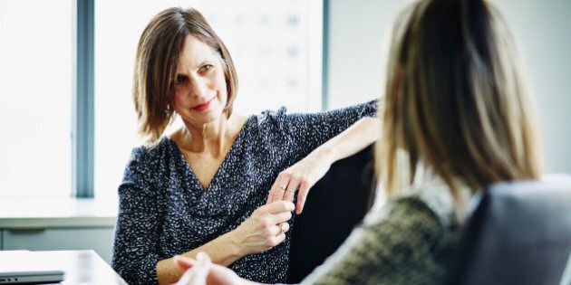 Mature businesswoman in discussion with female colleague at conference table in office