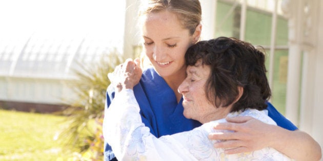 Young female nurse and senior woman embracing.