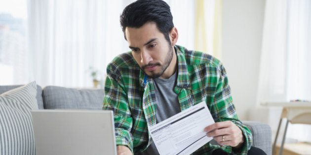 Mixed race man paying bills in living room