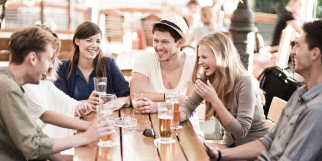 Group of young cheerful people having fun drinking beer outdoors.