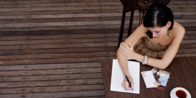 Woman writing postcards at table