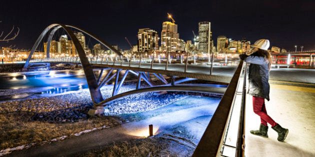Women enjoys a view of Calgary at night from the George C. King Bridge.