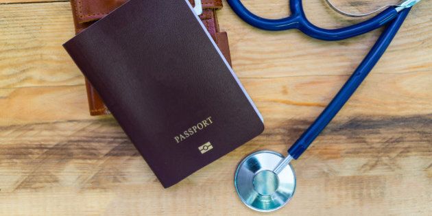Medical tourism concept. Stethoscope with passport on wooden table.