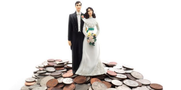 Plastic wedding couple on a pile of coins - money concept