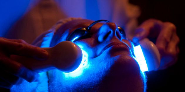 Woman receiving an led blue light therapy treatment during her facial. Low key photo shot in the darkened room; treatment is often performed in dim light to enhance relaxation.