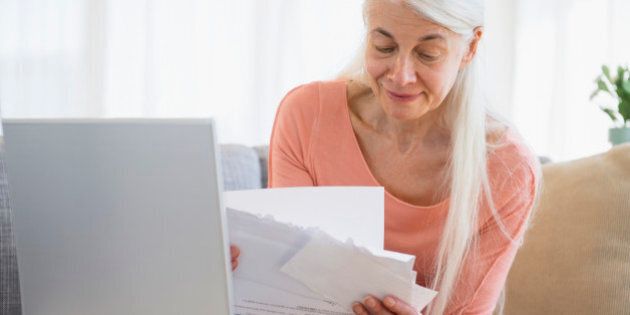 Senior woman going over bills with laptop