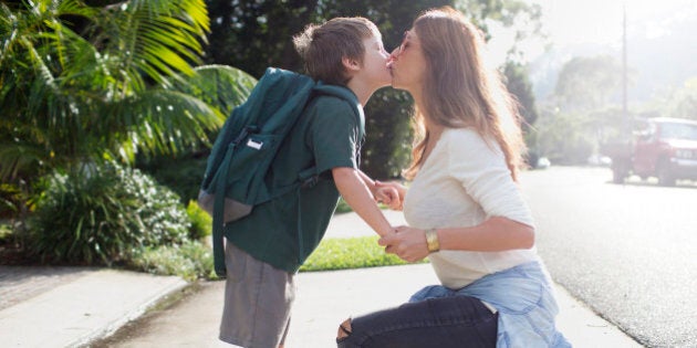 Boy kissing mother goodbye walking to school