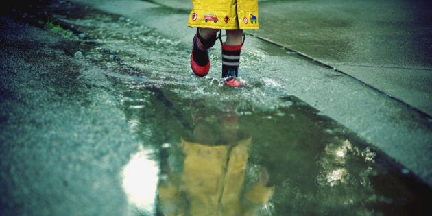 Child walking on puddles during in rainy day.