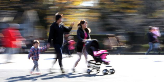 TO GO WITH Japan-law-family-women,ADVANCER by Harumi OZAWAThis picture taken on December 12, 2015 shows a family strolling at a park in Tokyo. Japan's top court will rule this week on a pair of 19th century family laws that critics blast as sexist and out of touch. The Supreme Court will weigh in on the legality of a six-month ban on women remarrying after divorce and another law that requires spouses to have the same surname, in a highly anticipated decision set for on December 16. AFP PHOTO / Yoshikazu TSUNO / AFP / YOSHIKAZU TSUNO (Photo credit should read YOSHIKAZU TSUNO/AFP/Getty Images)
