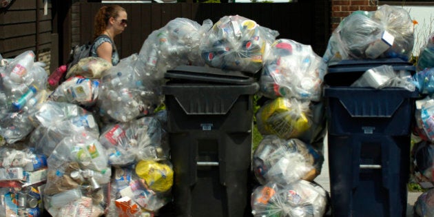 GARBAGE DAY- 08/04/09 - TORONTO - A pedestrian walks past a mix of garbage and recycling outside a Gerrard St. E row of rooming houses. The first garbage day following the municipal workers strike brought sickly sweet smells and stockpiles of garbage to city curbs in certain parts of the city. - (Photo by Jim Rankin/Toronto Star via Getty Images)