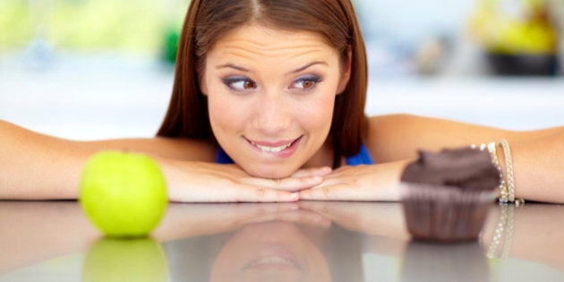 Pretty young woman trying to choose between unhealthy and healthy food options